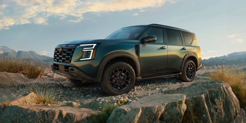 A powerfull SUV Nissan Armada parked atop rocky terrain under a wide open sky.
