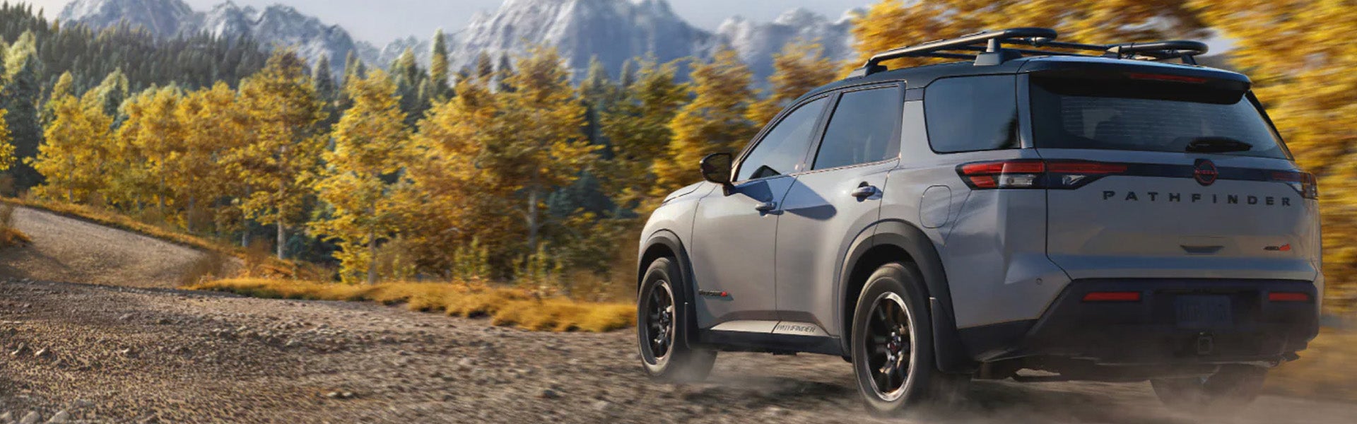 Silver Nissan Pathfinder SUV driving on a scenic mountain trail.