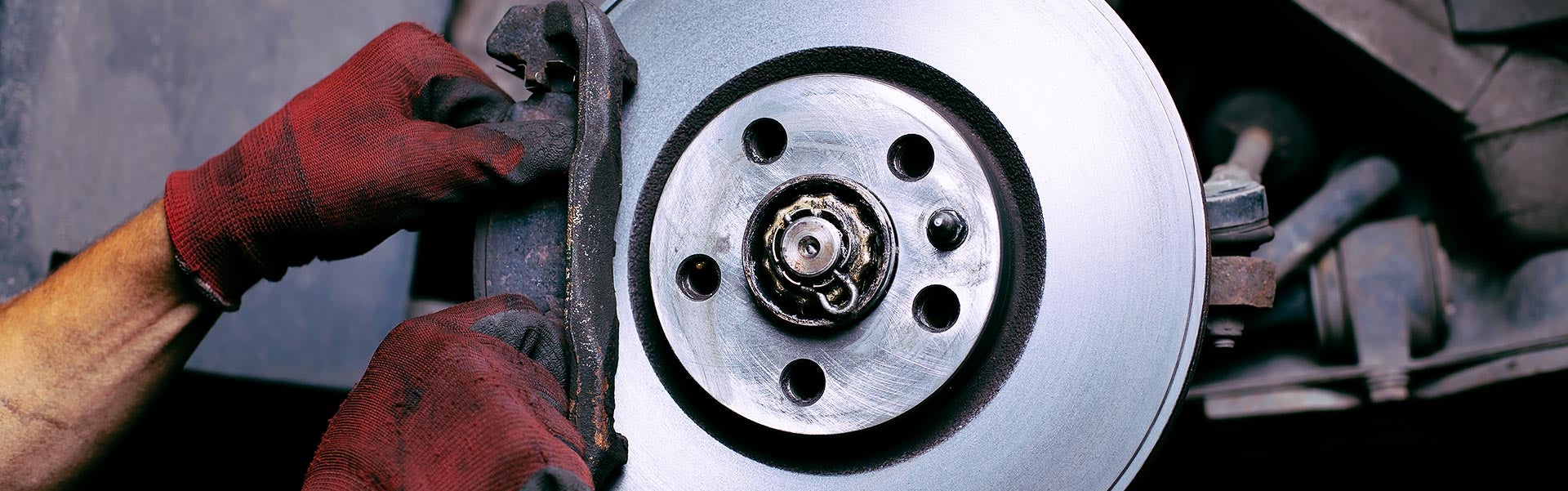 Technician inspecting a vehicle brake rotor and caliper assembly during brake maintenance service.