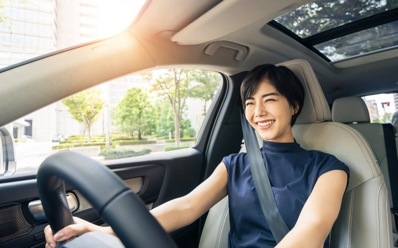 A smiling women driving a nice car.